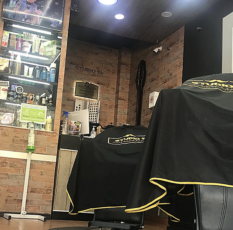 Sillones con capa negra de ribete amarillo, la vitrina iluminada de productos y el muro de ladrillo con el nombre Studio 10